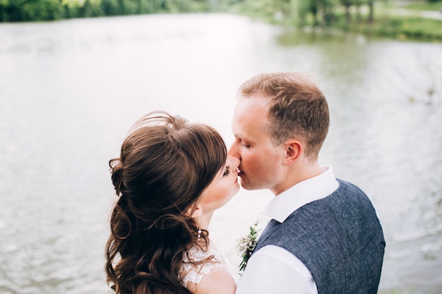 Elegante Braut und Bräutigam, die zusammen draußen an einem Hochzeitstag aufwerfen