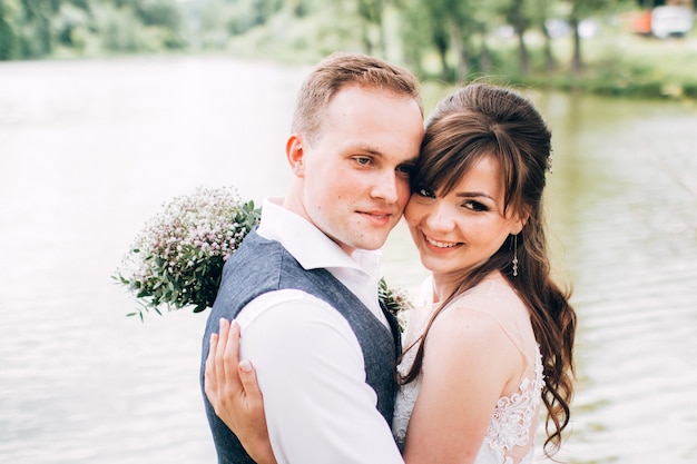 Elegante Braut und Bräutigam, die zusammen draußen an einem Hochzeitstag aufwerfen