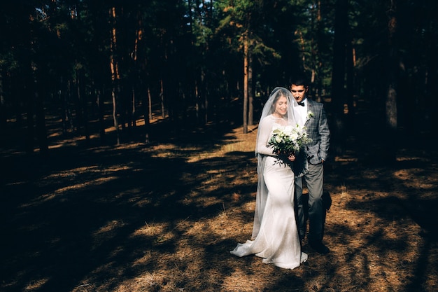 Elegante Braut und Bräutigam, die zusammen draußen an einem Hochzeitstag aufwerfen