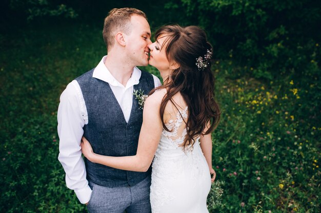 Elegante Braut und Bräutigam, die zusammen draußen an einem Hochzeitstag aufwerfen