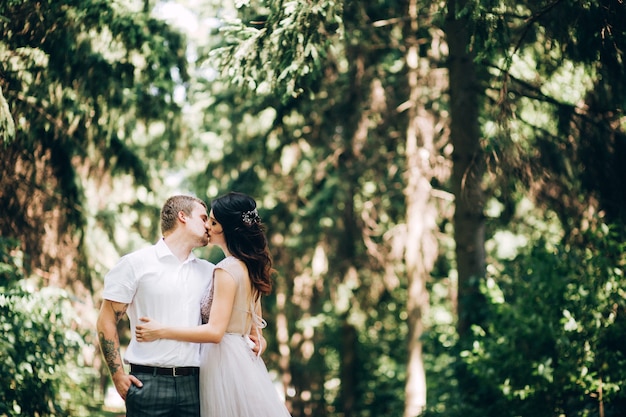 Elegante Braut und Bräutigam, die zusammen draußen an einem Hochzeitstag aufwerfen