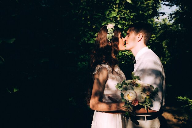 Elegante Braut und Bräutigam, die zusammen draußen an einem Hochzeitstag aufwerfen