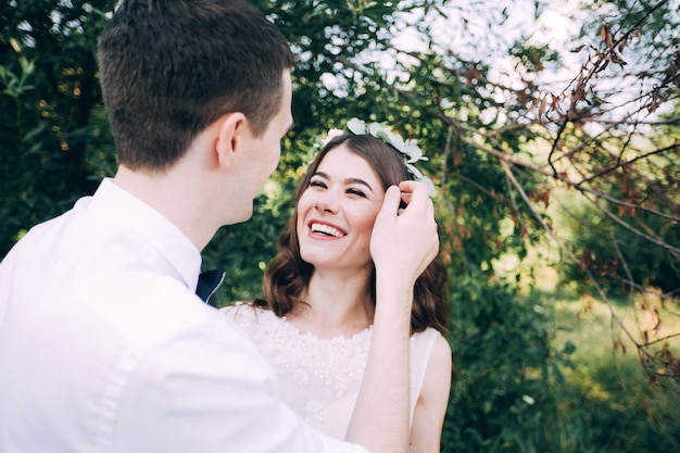 Elegante Braut und Bräutigam, die zusammen draußen an einem Hochzeitstag aufwerfen