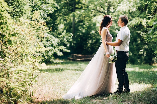 Elegante Braut und Bräutigam, die zusammen draußen an einem Hochzeitstag aufwerfen