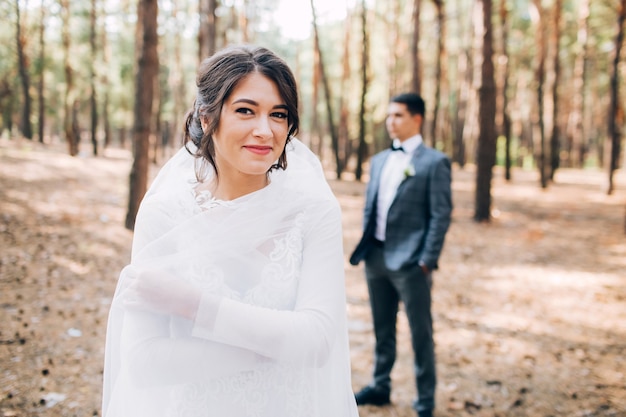 Elegante Braut und Bräutigam, die zusammen draußen an einem Hochzeitstag aufwerfen