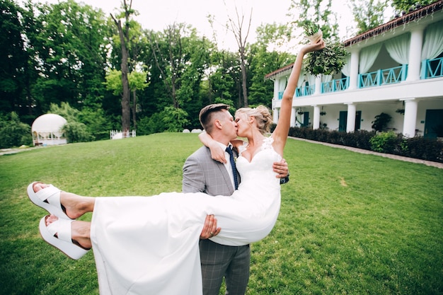 Elegante Braut und Bräutigam, die zusammen draußen an einem Hochzeitstag aufwerfen