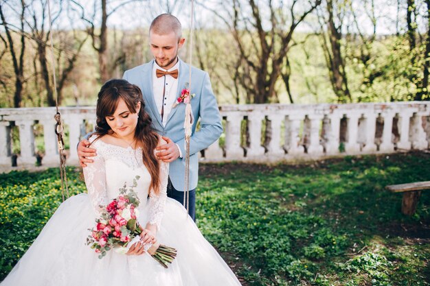 Elegante Braut und Bräutigam, die zusammen draußen an einem Hochzeitstag aufwerfen