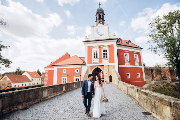 Elegante Braut und Bräutigam, die zusammen draußen aufwerfen