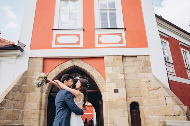 Elegante Braut und Bräutigam, die zusammen draußen aufwerfen