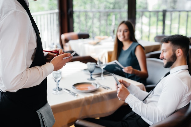 Foto un elegante camarero sirve a una pareja joven que tuvo una cita en un restaurante gourmet. atención al cliente en el catering.