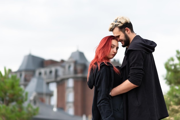 Elegante casal apaixonado em roupas pretas caminha no parque e abraça Lindo casal de descolados abraçando no fundo da casa Conceito de amor e estilo de vida da juventude