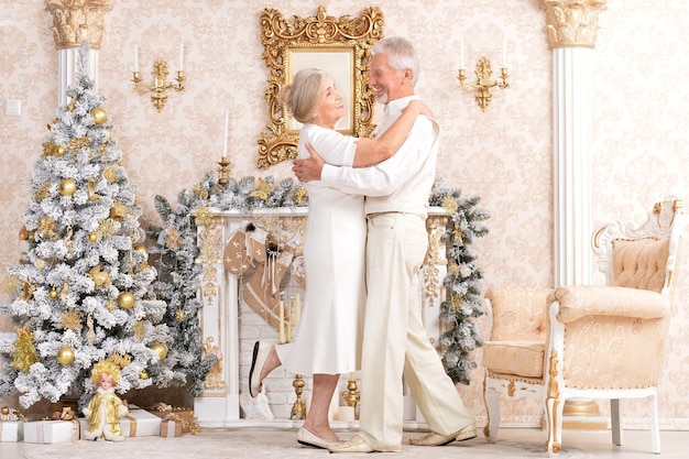 Elegante casal de idosos dançando perto da árvore de natal