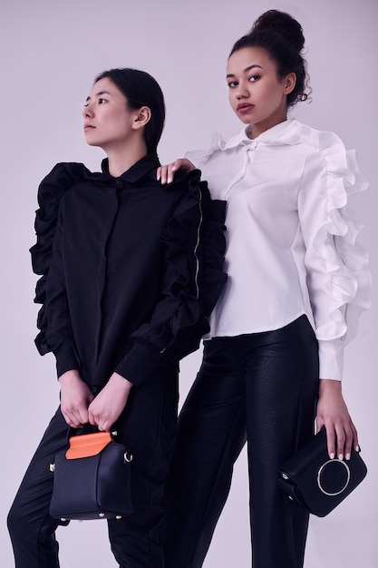 Elegante casal de mulheres negras e asiáticas em elegantes ternos preto e brancos
