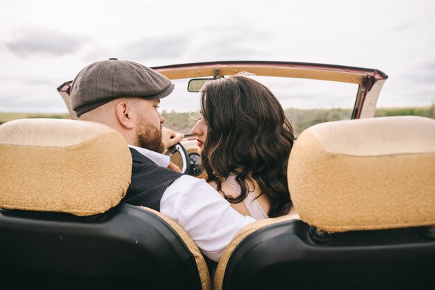 Foto elegante casal de noivos beijando no carro retrô