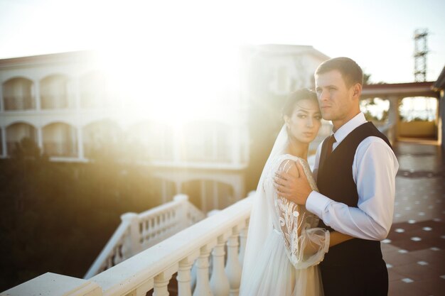 Elegante casal de recém-casados felizes posando ao pôr do sol Sexy beijando elegante casal de amantes ao pôr do sol