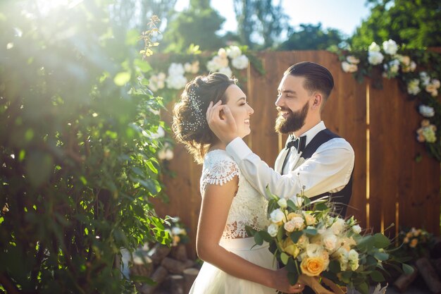 Foto elegante casal de recém-casados felizes posando ao sol linda noiva e elegante noivo momento romântico