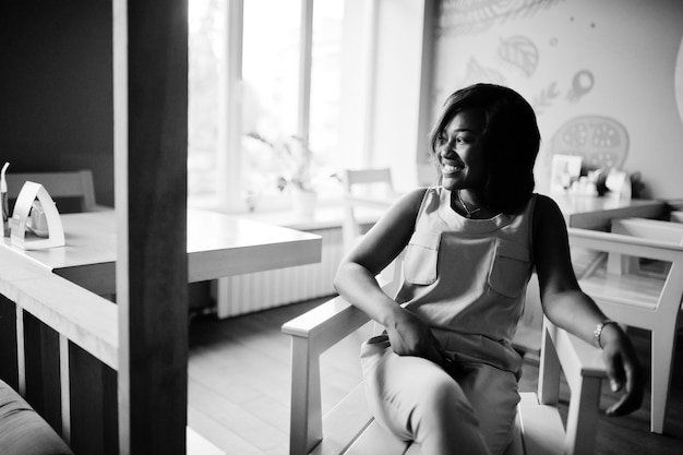 Elegante chica afroamericana posada en un café moderno