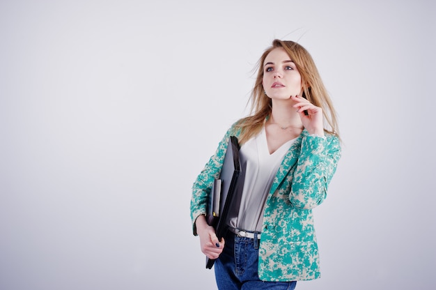 Elegante chica rubia en chaqueta y jeans con cuaderno diario y portátil en manos contra