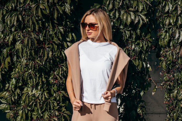 Elegante chica rubia vestida con camiseta blanca y gafas