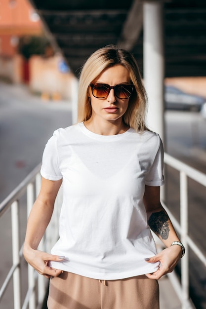 Elegante chica rubia vestida con camiseta blanca y gafas