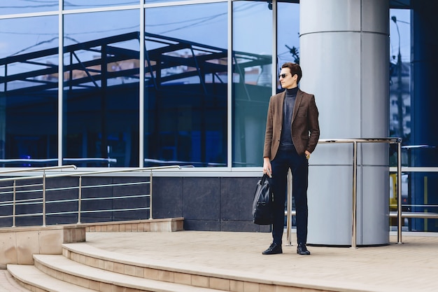 Elegante chico atractivo en chaqueta con pasaporte y entradas.