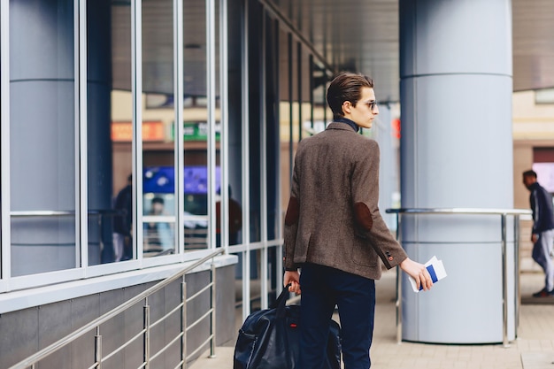 Elegante chico atractivo en chaqueta con pasaporte y entradas.