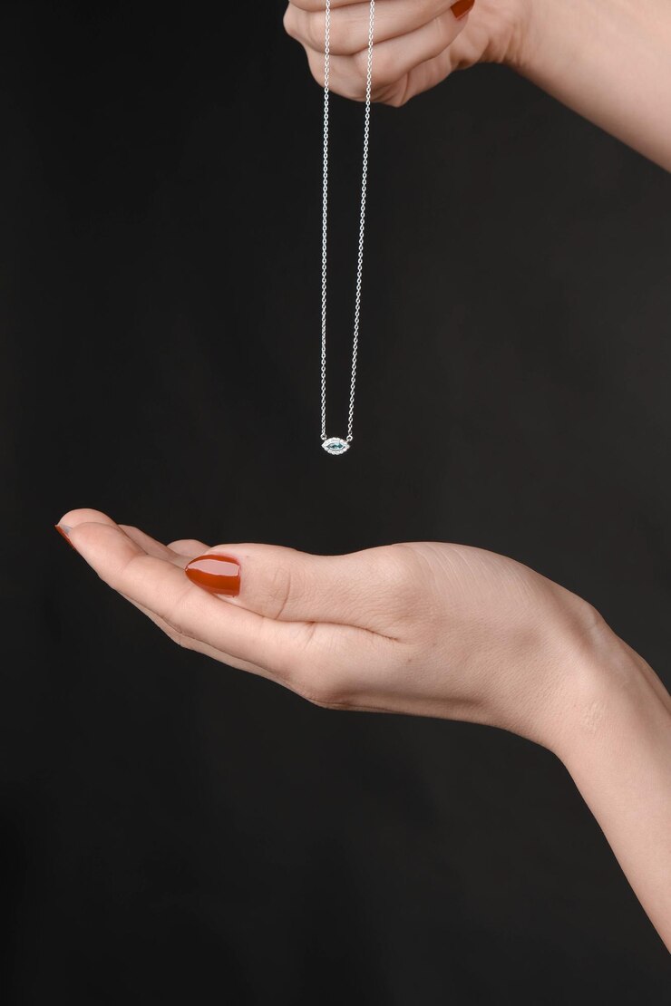 Foto elegante colar de prata com uma pedra preciosa segurada pela mão de uma mulher