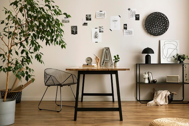 La elegante composición del acogedor interior de la oficina con una silla de metal, una mesa de madera, un póster de plantas y accesorios personales. Plantilla de decoración del hogar.