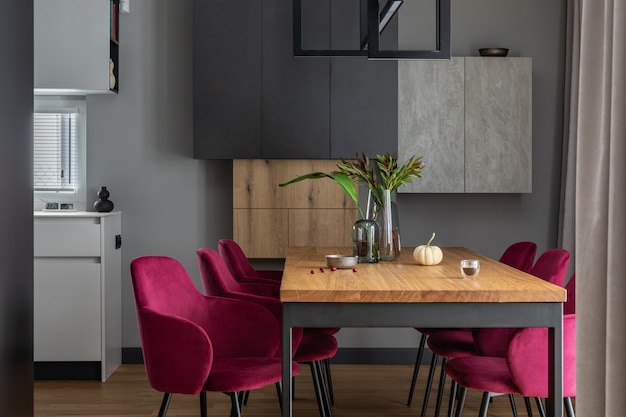 Elegante composición interior del comedor con sillas de terciopelo, lámparas de mesa de madera de diseño y hermosos accesorios personales Espacio abierto Paredes de concreto Decoración casera moderna Plantillas