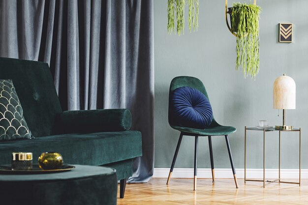 Elegante composición del interior de la sala de estar del apartamento de lujo con sofá de diseño, silla, mesa de café y accesorios. Paredes verdes y parquet de madera.