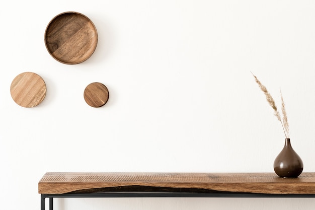 Elegante composición del interior de la sala de estar con paredes blancas, plantas verdes en macetas de diseño hipster blanco en la consola escandinava de madera. Concepto minimalista. Copie el espacio. Plantilla.