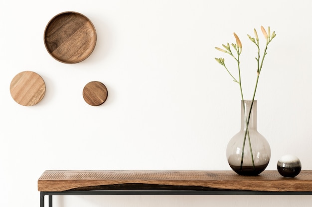 Elegante composición del interior de la sala de estar con paredes blancas, plantas verdes en macetas de diseño hipster blanco en la consola escandinava de madera. Concepto minimalista. Copie el espacio. Plantilla.