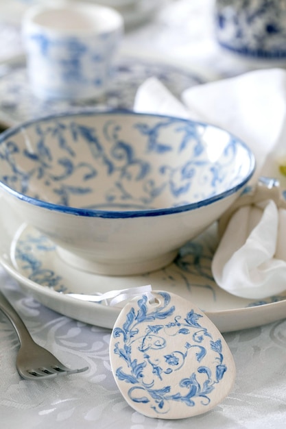 Elegante configuração de mesa de páscoa com ornamento marinho vazio pintado pratos de porcelana e tigelas decorações de ovos de páscoa na toalha de mesa branca jantar de férias de páscoa