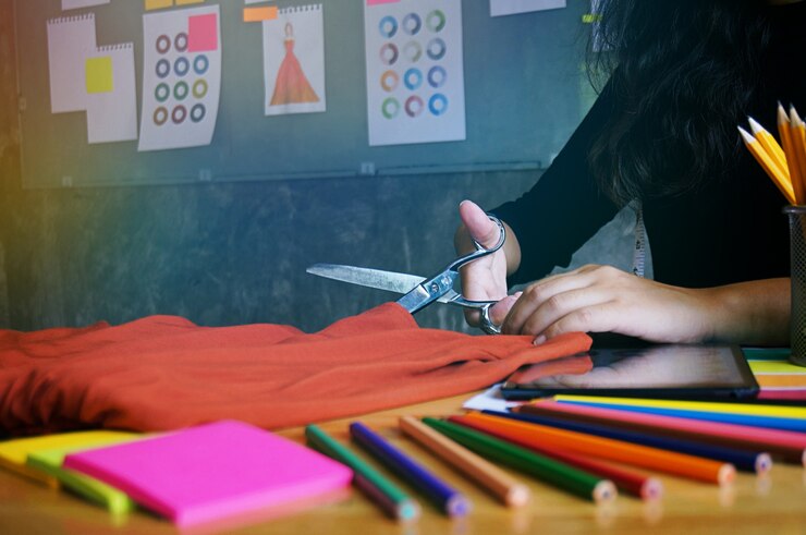 Foto elegante diseñador de moda tela de corte de nueva colección en el taller. concepto de diseño creativo.