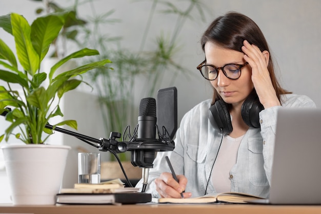 La elegante y educada mujer caucásica graba podcasts en un estudio de grabación o en su casa.