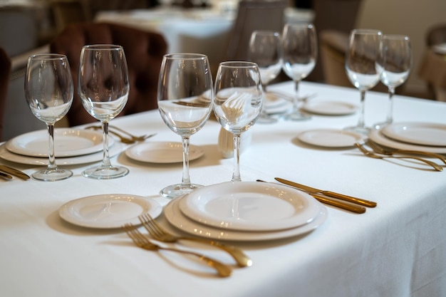 Elegante y elegante cubertería chapada en oro y mesa de platos blancos con platos vacíos