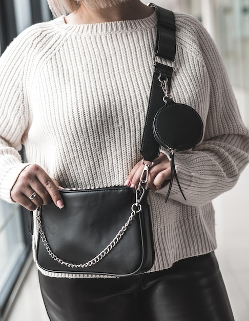 Elegante elegante jovem segurando uma bolsa de couro preta legal. Conceito de estilo. O conceito de sofisticação