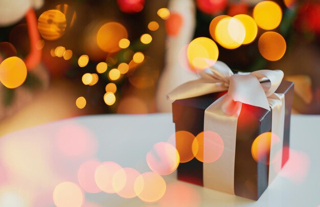 Elegante empaque de papel negro y un lazo beige Caja de regalo de Año Nuevo Luces brillantes de la guirnalda