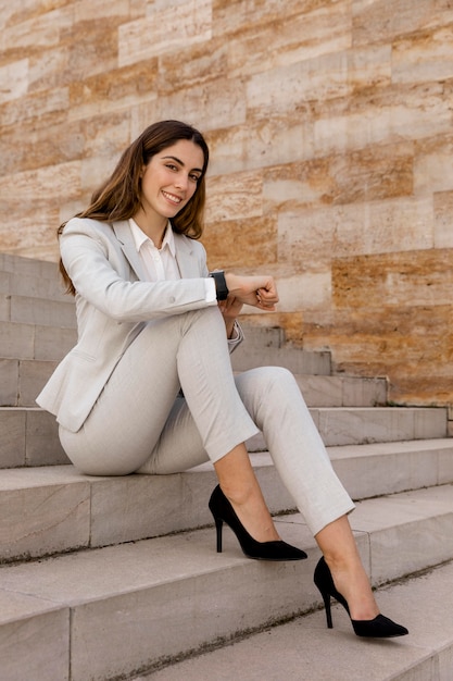 Elegante empresaria con smartwatch posando en las escaleras al aire libre