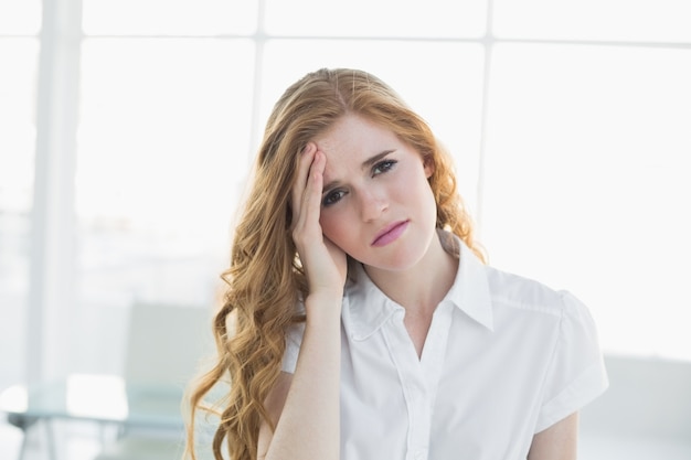 Elegante empresaria sufre de dolor de cabeza en la oficina