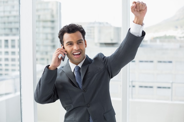 Elegante empresário alegre usando celular no escritório