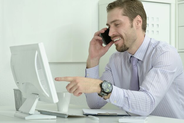 Elegante empresario con computadora y teléfono en la oficina