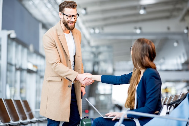 Elegante empresário de casaco encontrando-se com uma empresária na sala de espera do aeroporto