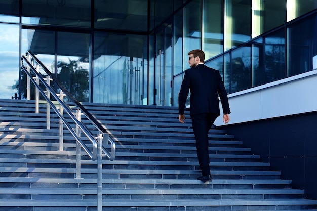 Foto elegante empresário de sucesso sobe as escadas do prédio de escritórios