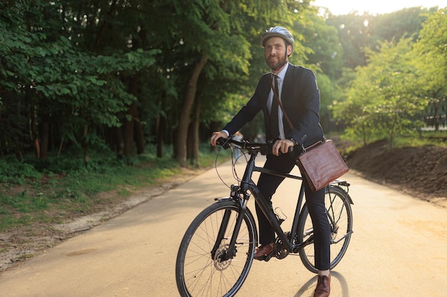 Foto elegante empresario masculino montando en bicicleta mientras llega al lugar de trabajo