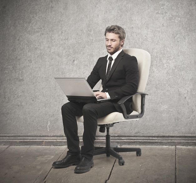 Foto elegante empresario sentado en una silla con su computadora portátil