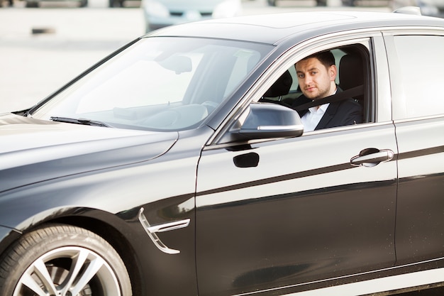 Elegante empresário vestido de terno, fixando o cinto de segurança antes de dirigir seu carro