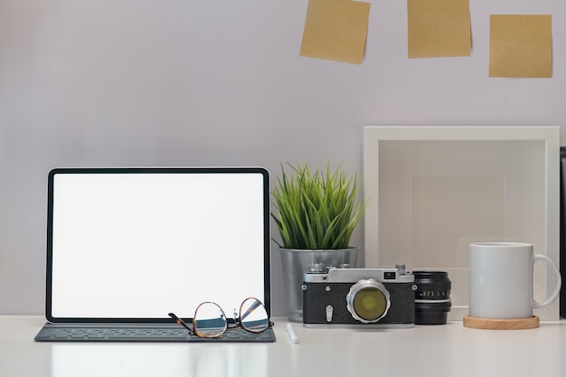 Elegante escritorio de trabajo, cámara vintage, tableta de pantalla en blanco y gadget.