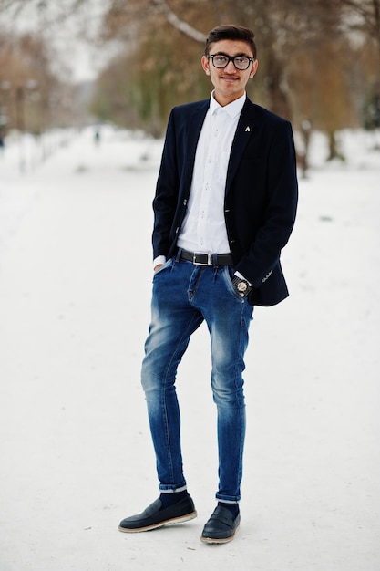 Elegante estudiante indio con traje y gafas posó en el día de invierno al aire libre