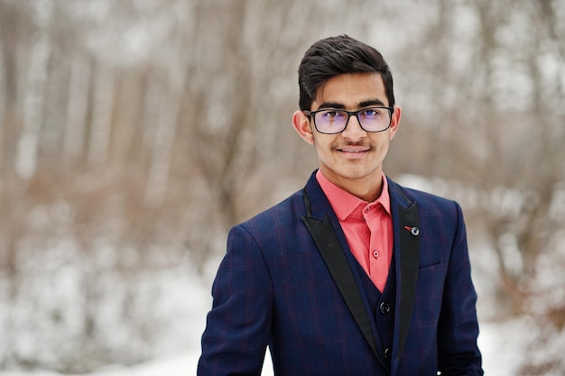 Elegante estudiante indio con traje y gafas posó en el día de invierno al aire libre